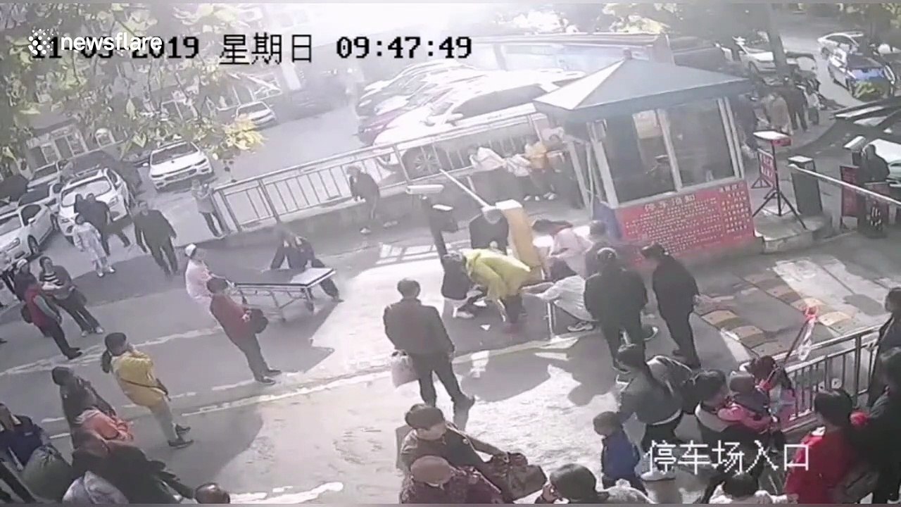 Passersby help paramedics tend to woman giving...