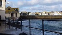 Pedestrians dodge crashing waves in St Ives, Cornwall
