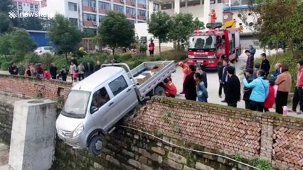 Firefighters save driver stuck inside truck hanging off 13ft-high wall