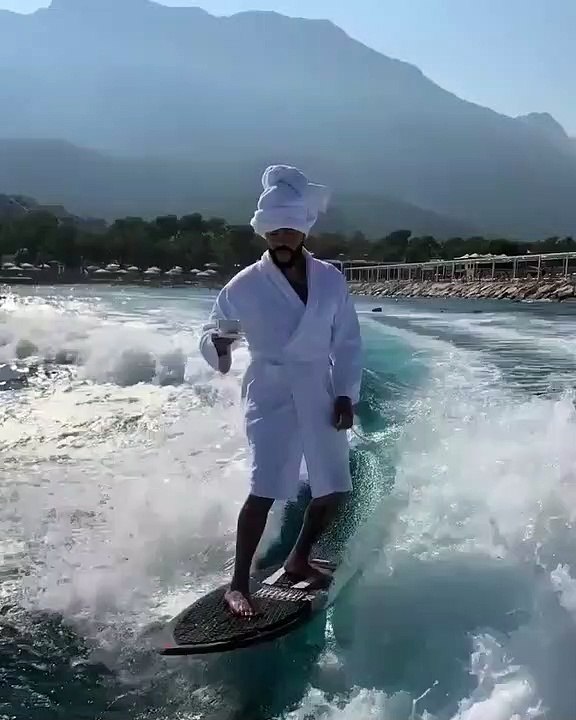 Ce gars fait du surf en peignoir tout en buvant du café.