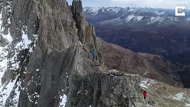 Il tient debout sur un rocher en équilibre en haut d'une montagne !