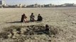 Varios hombres se entierran en una playa de Pakistán durante el eclipse solar