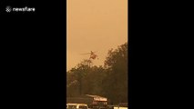 Water-dropping helicopter waters down NSW fires as it continues to grow near Batemans Bay evacuation center