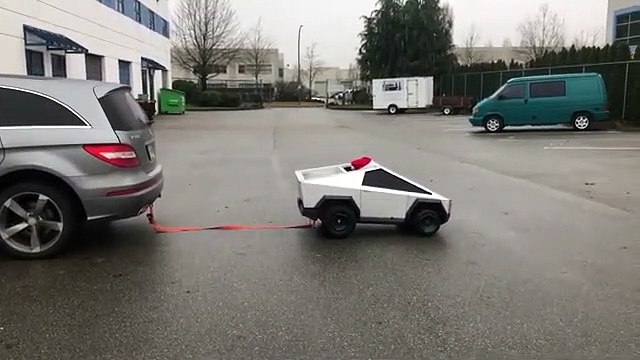 Un mini cybertruck conduit par un enfant tire une voiture