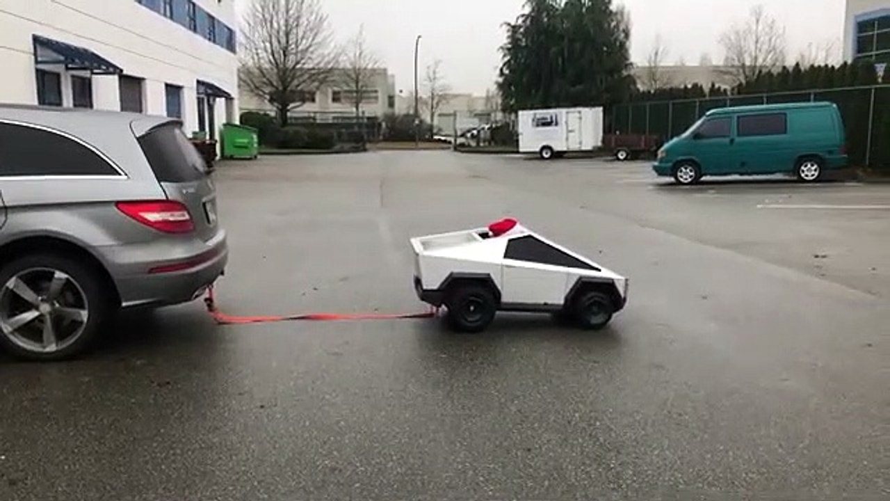 Un mini cybertruck conduit par un enfant tire une voiture