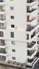 Un enfant s’amuse à marcher sur le rebord d’un immeuble pour passer du balcon à la fenêtre