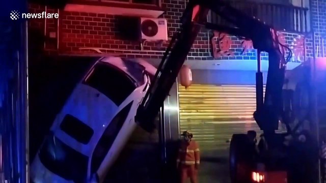 Chinese firefighters rescue motorist trapped inside car stuck vertically on shop gates