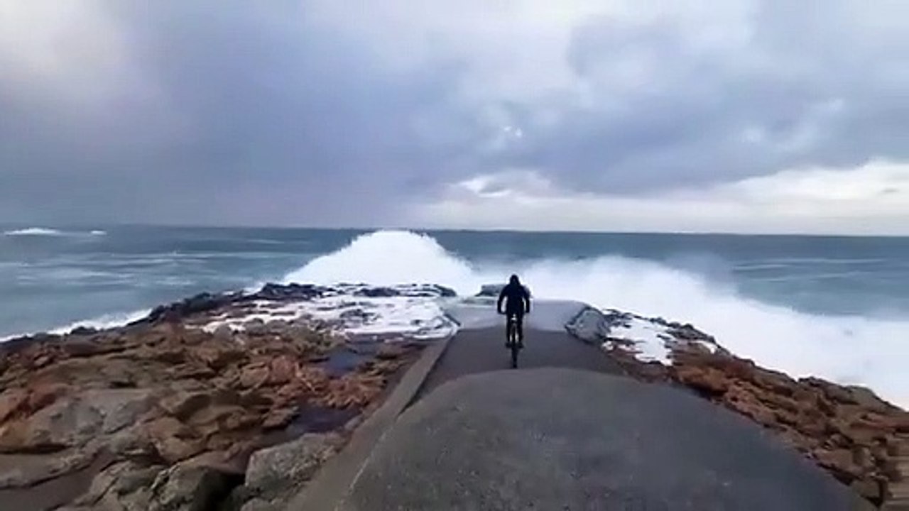 Ce cycliste se rapproche un peu trop près du bord de mer pendant la tempête en Espagne