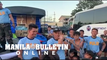 A policeman entertains kid-evacuees housed at Bauan Technical High School in Bauan town, Batangas