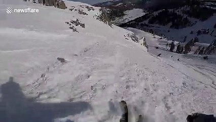 Skier laughs as he lands 360 off side of cliff barely missing rocks
