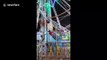 India fairground staff perform nerve-wracking stunt by hanging onto Ferris wheel as it spins around at speed