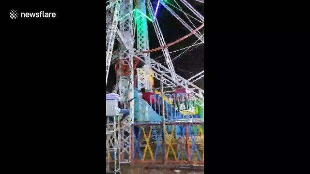 India fairground staff perform nerve-wracking stunt by hanging onto Ferris wheel as it spins around at speed