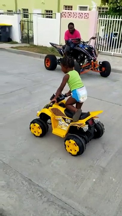 A Toddler learns to drive four Wheeler with his dad