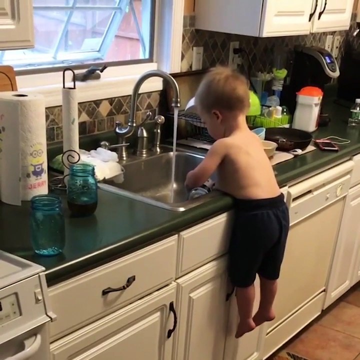 Cet enfant fait la vaisselle bien calé sur son ventre