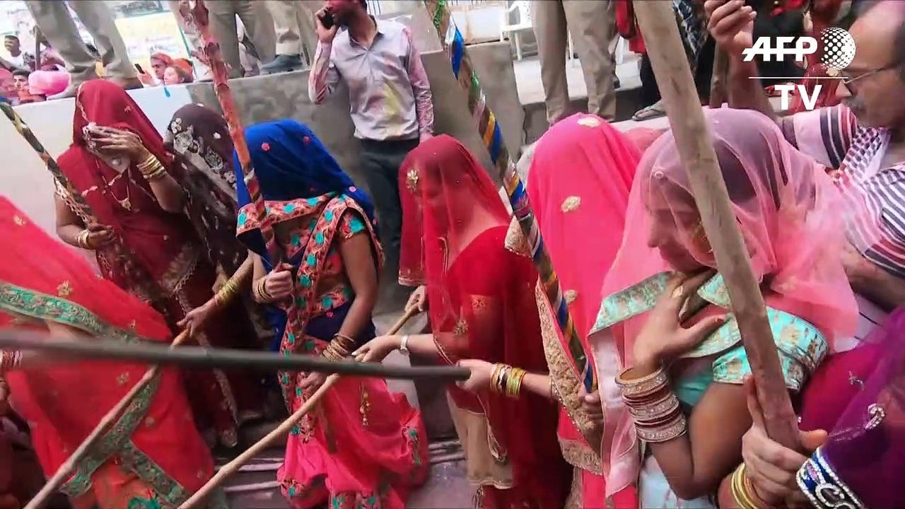 Männer kriegen Schläge beim 'Lathmar Holi'-Fest