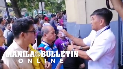 Employees and visitors of Manila City Hall queue for a handheld thermal scanner