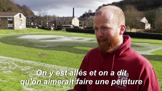 Un artiste peint le portrait géant de Greta Thunberg sur un terrain d'école