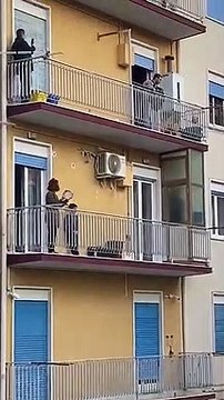 Les habitants d'un quartier confiné sortent au balcon pour improviser un petit concert