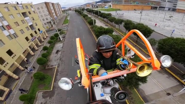 Hissé sur la grue de son camion, ce pompier équatorien joue de la trompette pour les habitants confinés