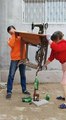 Ces deux Asiatiques réussissent à maintenir en équilibre une table de machine à coudre dont l’un des pieds est posé sur la tête d’une bouteille.