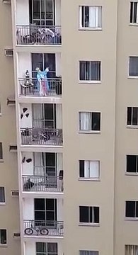 Mulher vestida de santa presta homenagem à Nossa Senhora da Penha da varanda de casa