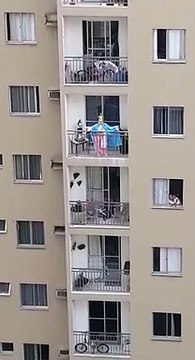 Mulher vestida de santa presta homenagem à Nossa Senhora da Penha da varanda de casa