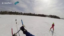 Father pulls son along while kite skiing on frozen lake in Canada