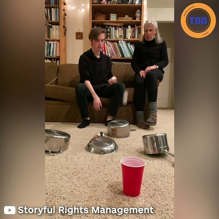 Accompagné de sa mère, ce jeune s'amuse avec une balle de ping pong et des casseroles !