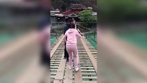 Terrifiée elle traverse un pont en bois suspendu au dessus d'une rivière