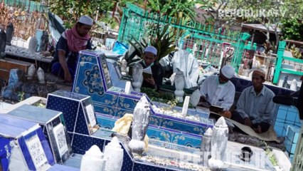 Warga menggunakan masker saat berziarah ke makam keluarganya di Tempat Pemakaman Umum (TPU).
