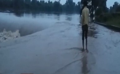 सैलाब में ज़िंदगी से खिलवाड़, पानी से भरे पुल को पार करते लोग