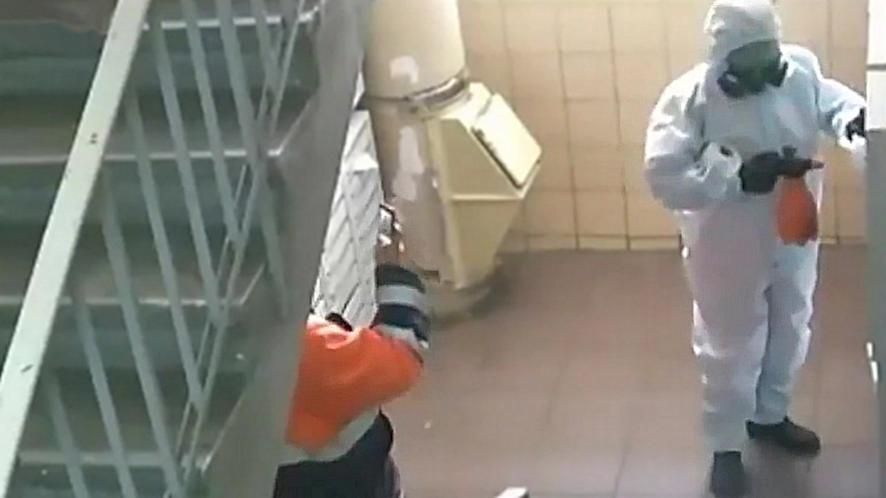 Deux employés font semblant de désinfecter un immeuble du coronavirus