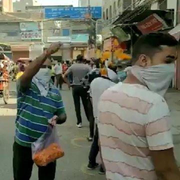 A Delhi man showers flower petals on people standing in queue outside a liquor shop