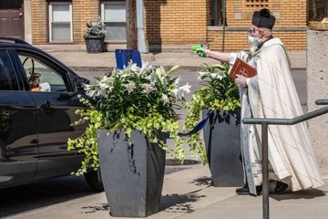 Un prêtre bénit les fidèles à distance avec un pistolet à eau