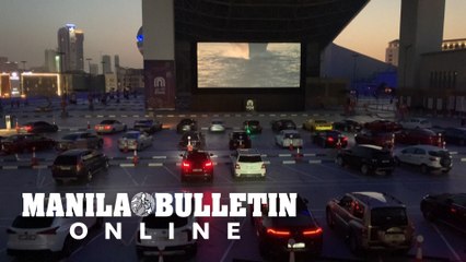 People watch a movie in their cars at a drive-in cinema in Dubai