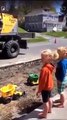 Operador de escavadora usa máquina para encher camiões de brincar para crianças