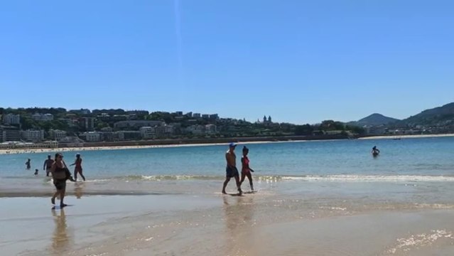 Los donostiarras aprovechan la bajamar para pasear por la orilla en La Concha