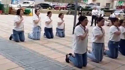 Chinese employees kneel down and chant slogans to give thanks to their company