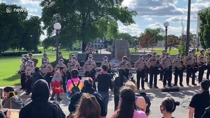 In front of line of police, Native American activists engage in dance in front of Minnesota state capitol