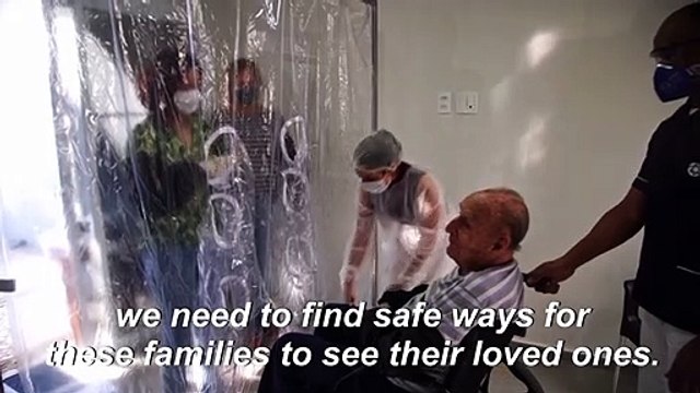 Nursing home residents hug loved ones through a plastic 'hug curtain' amid pandemic