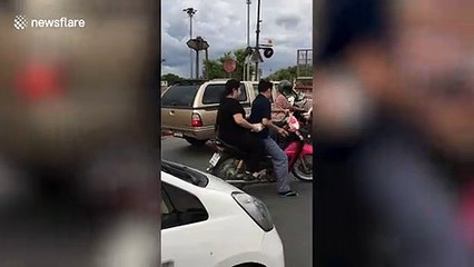 Hungry wild monkey leaps onto motorcycle to steal passenger's food