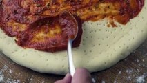 Avraham Chaim Kerendian-preparing-a-pizza-dough-covering-it-with-salsa