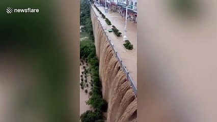 Rainfall causes flood and creates waterfall on bridge in southern China