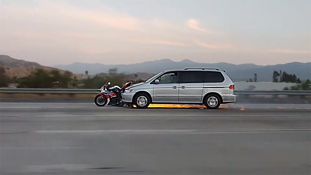 Une voiture roule en poussant une moto encastrée dans le par-chocs