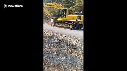 Workers in Vietnam use old tires to avoid damaging road when moving crawler excavator