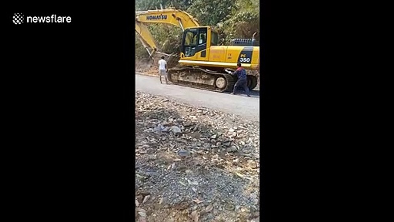 Workers in Vietnam use old tires to avoid damaging road when moving crawler excavator
