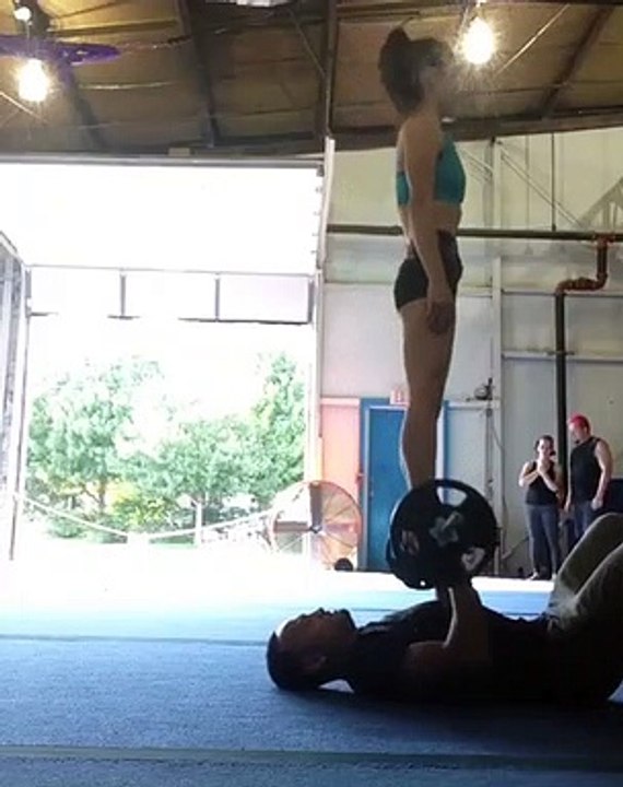 Il fait ses haltères avec une femme debout en équilibre sur la barre !