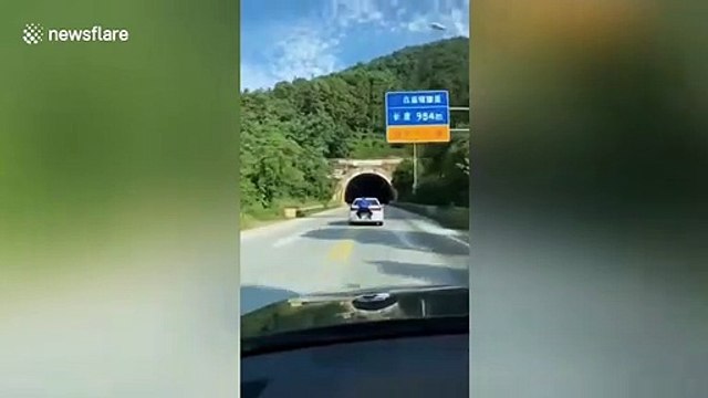 Chinese CD seller drives away trying to escape fine with official hanging onto to his car