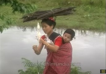 Woman spinning while on the go, with child on back, wood pile on head!