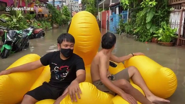 Residents in Thailand use inflatable rubber duck to ride to the shops after rain flooded roads